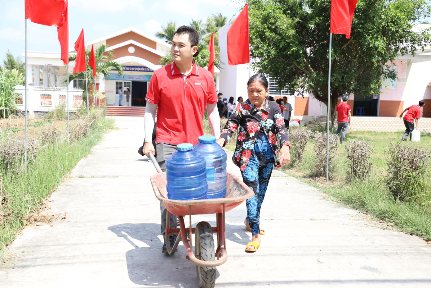 Đón nhận bình nước từ hệ thống máy lọc nước trong ngày vận hành, bà Hồ Thị Khạ (bên phải, 64 tuổi, ấp Tân Hòa) cho biết lâu nay bà phải đổi nước ở đại lý gần nhà với giá 10.000 đồng (bình 20 lít) để uống và nấu ăn, còn tắm giặt thì dùng nước mưa dự trữ. “Giờ đây có hệ thống lọc nước gần bên, tôi đỡ phải mua nước hằng tháng, tiết kiệm được thêm một ít chi phí”, bà Khạ chia sẻ.