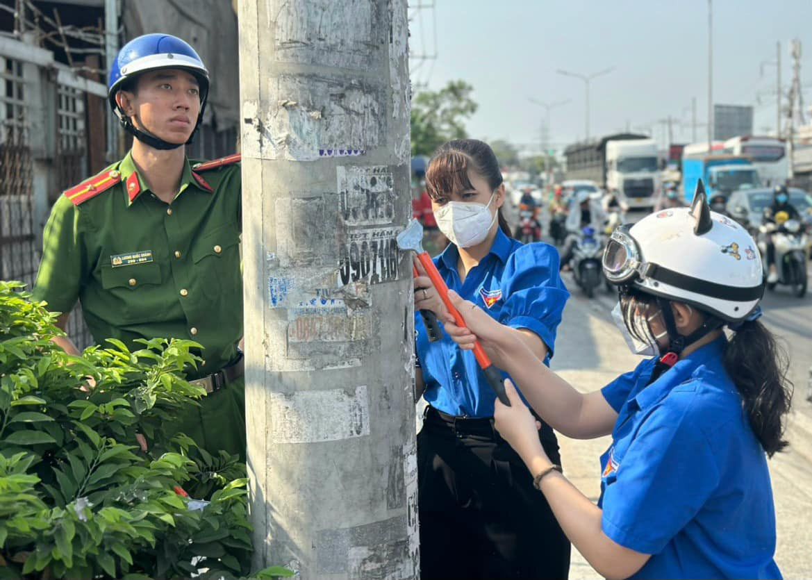 Các đoàn viên thanh niên, chiến sĩ công an ở huyện Bình Chánh thực hiện bóc xóa các sản phẩm quảng cáo, rao vặt trái phép.