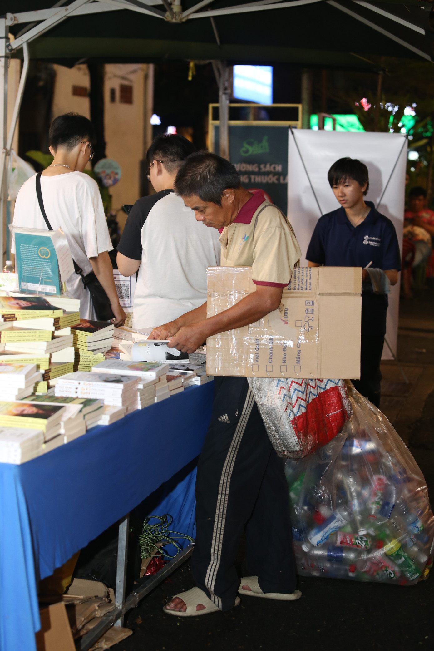 Ông Huy chăm chú đọc một số tựa sách trên bước đường mưu sinh đêm giao thừa. Ảnh: Ngô Tùng