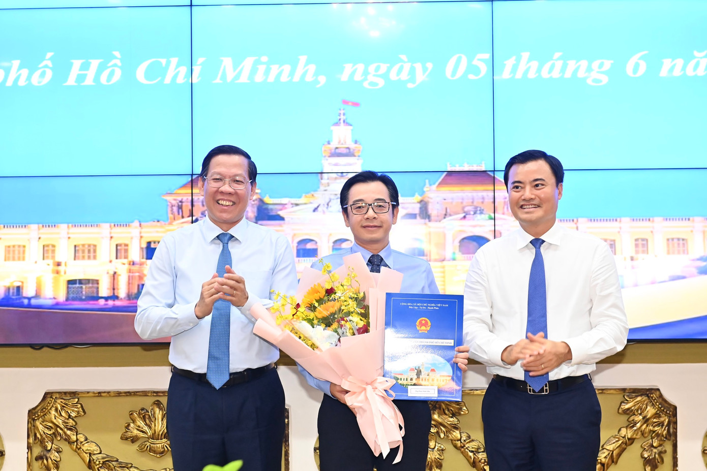 Chủ tịch UBND TPHCM Phan Văn Mãi và Phó Chủ tịch UBND TPHCM Bùi Xuân Cường trao quyết định và hoa chúc mừng ông Phạm Minh Mẫn. Ảnh: Việt Dũng