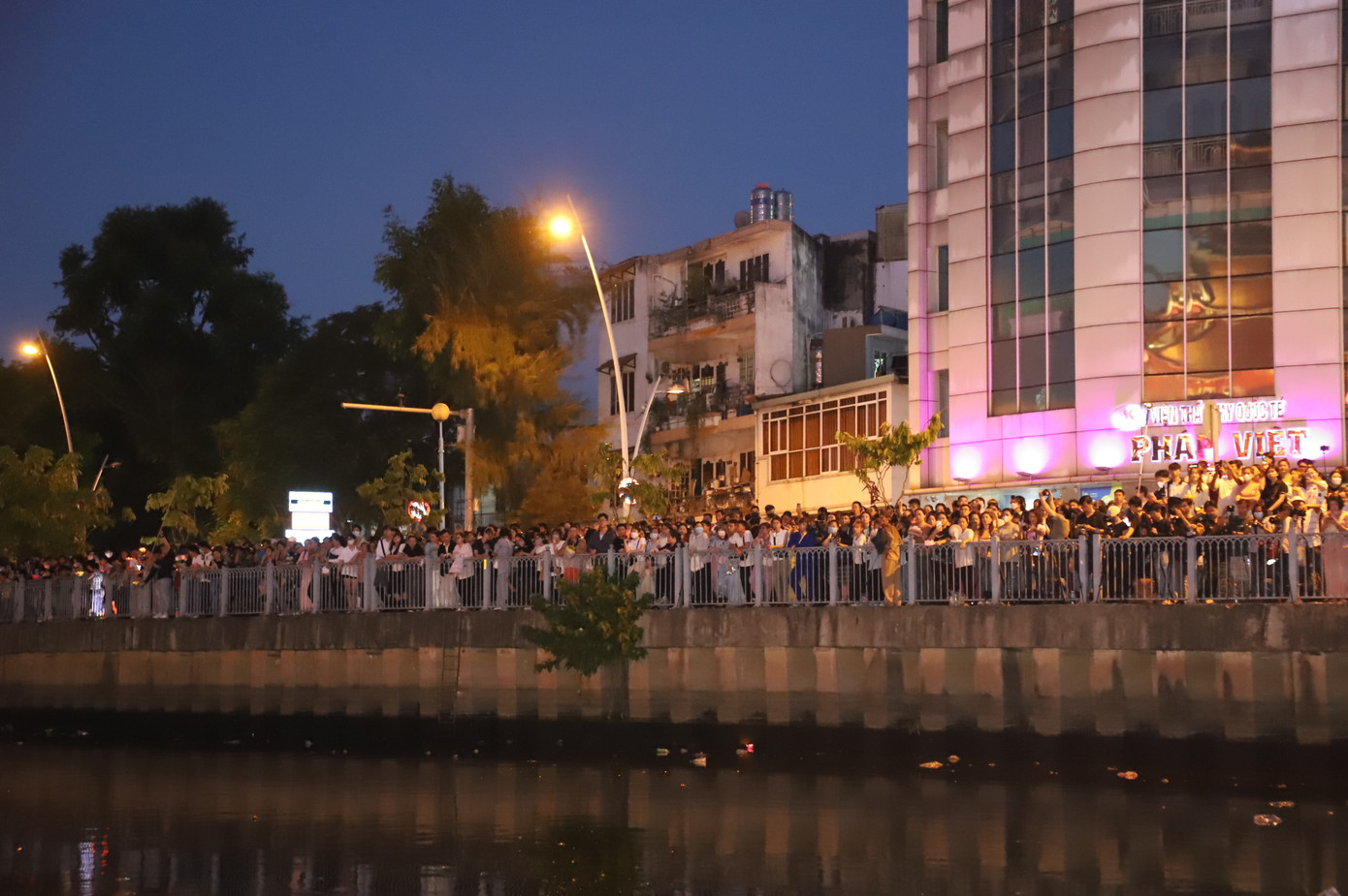 Phía bờ đối diện chùa, hàng nghìn bà con phật tử, nhân dân đứng theo dõi buổi lễ và chuẩn bị thả hoa đăng.