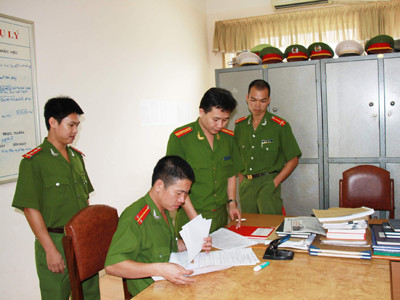 Thượng úy Bùi Việt Hùng (ngoài cùng bìa trái) cùng đồng đội nghiên cứu hồ sơ các vụ án Ảnh: Trường Phong