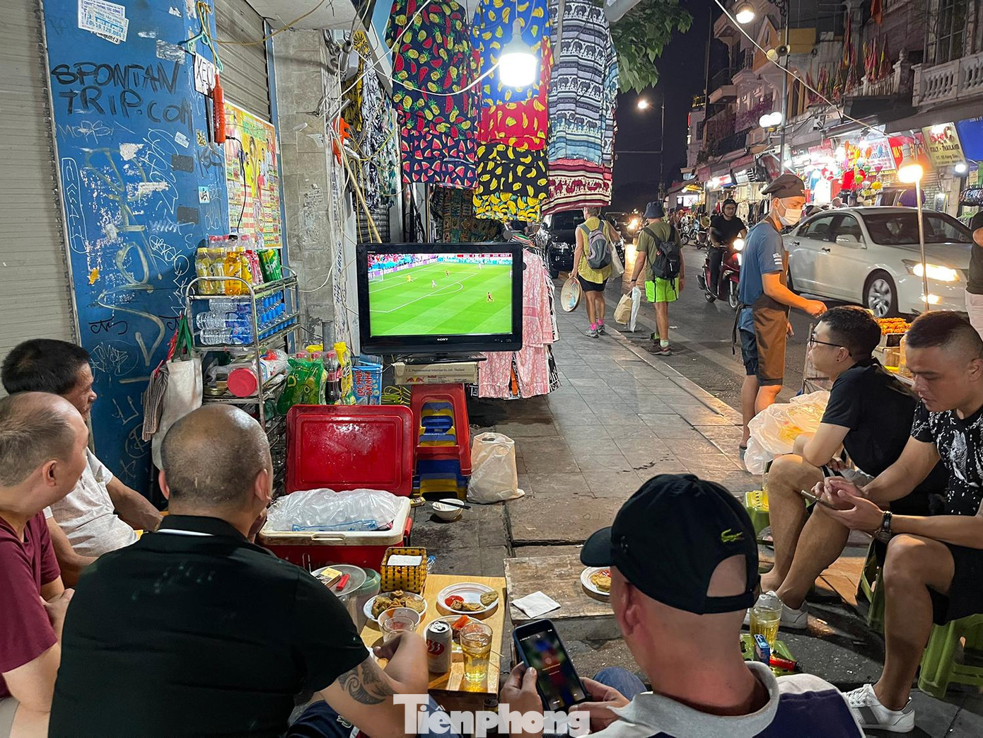 Trên nhiều tuyến phố thủ đô, người đi đường không khó để bắt gặp hình ảnh màn hình tivi, máy chiếu và người hâm mộ theo dõi trận đấu. Trong ảnh: Người dân phố cổ Hàng Đào, quận Hoàn Kiếm mang ti vi ra vỉa hè ngồi xem trận bóng Morocco vs Croatia.