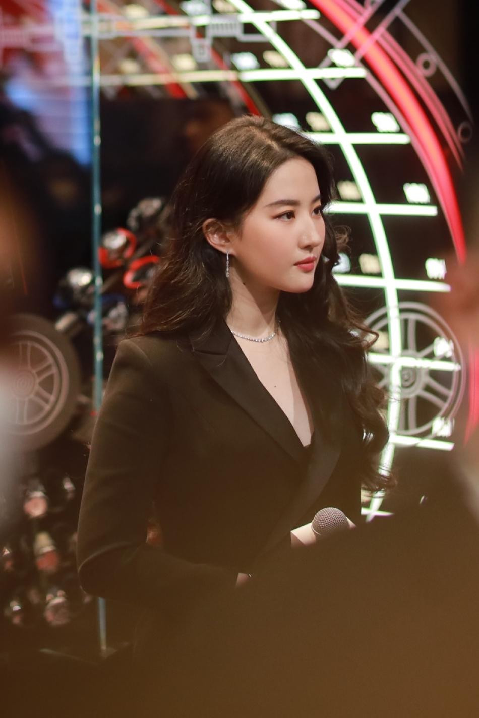 Tại sự kiện, Lưu Diệc Phi diện vest đen cách điệu ôm sát cơ thể. Mái tóc xoăn buông xõa. Gương mặt trang điểm tỉ mỉ, sử dụng phấn mắt và son môi màu cam.