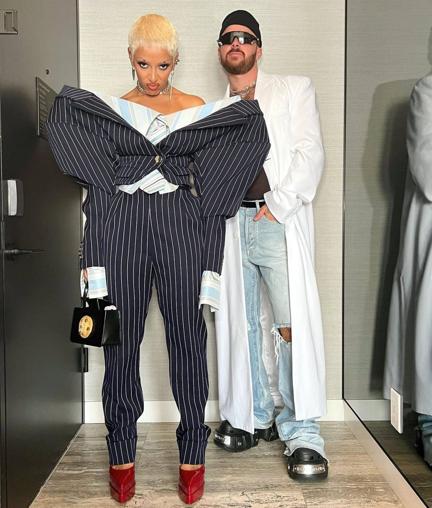 Khi cần quyến rũ, Doja Cat mặc những bộ đồ không thể gợi cảm hơn nhưng khi cần biến hóa trong trang phục cá tính, Doja Cat biết cách biến mình trở nên không giống ai. Tại Lễ trao giải Daily Front Row 2022, Doja Cat mặc bộ vest kẻ được thiết kế cách điệu ở phần vai áo đến từ nhà thiết kế Viktor &amp; Rolf. Nữ ca sĩ diện đôi giày chunky màu đỏ thẫm.