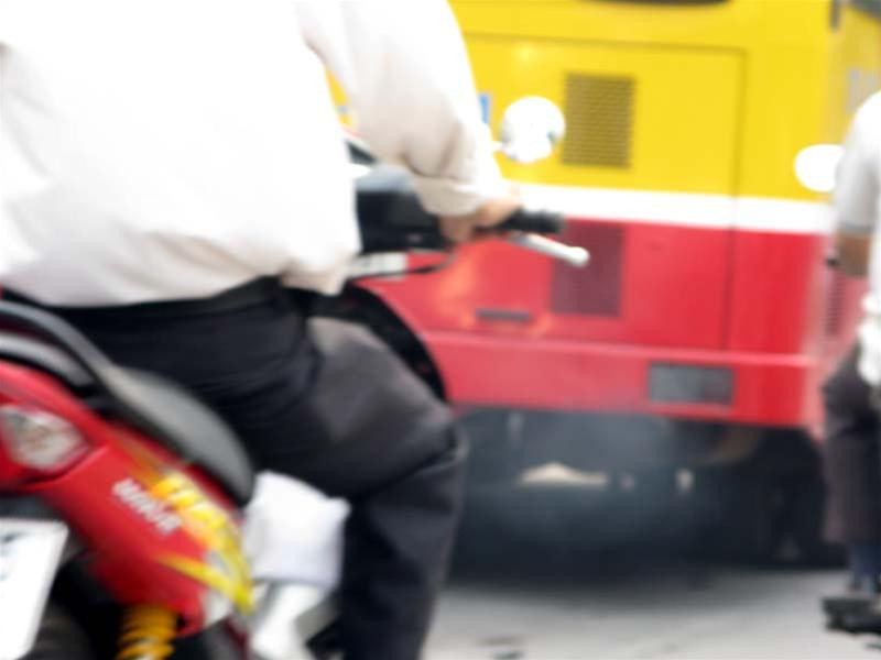 Người điều khiển xe máy đi sau xe buýt mà không đeo khẩu trang là lãnh trọn từng đợt khói đen ngòm. (ảnh chụp trên đường Phạm Hùng)