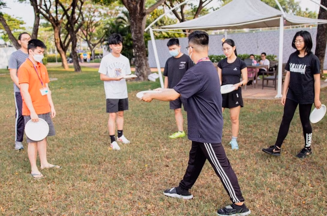 Các bạn trẻ mới tập chơi được các bạn đi trước chỉ dạy kỹ thuật ném đĩa bay.