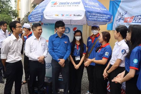 Anh Nguyễn Minh Triết (thứ ba bên trái) lắng nghe những báo cáo của đội hình tiếp sức mùa thi tại điểm thi THPT chuyên Trần Đại Nghĩa.