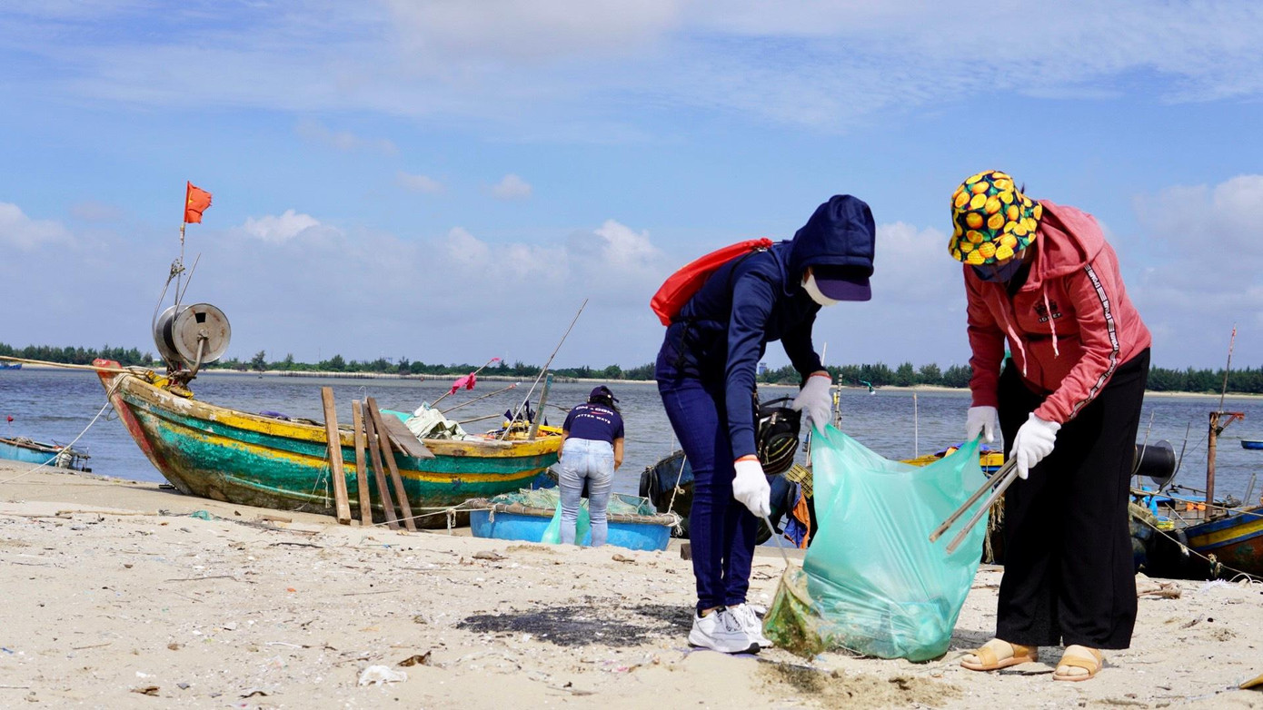 Các bạn trẻ đang nhặt rác ngoài bãi biển.