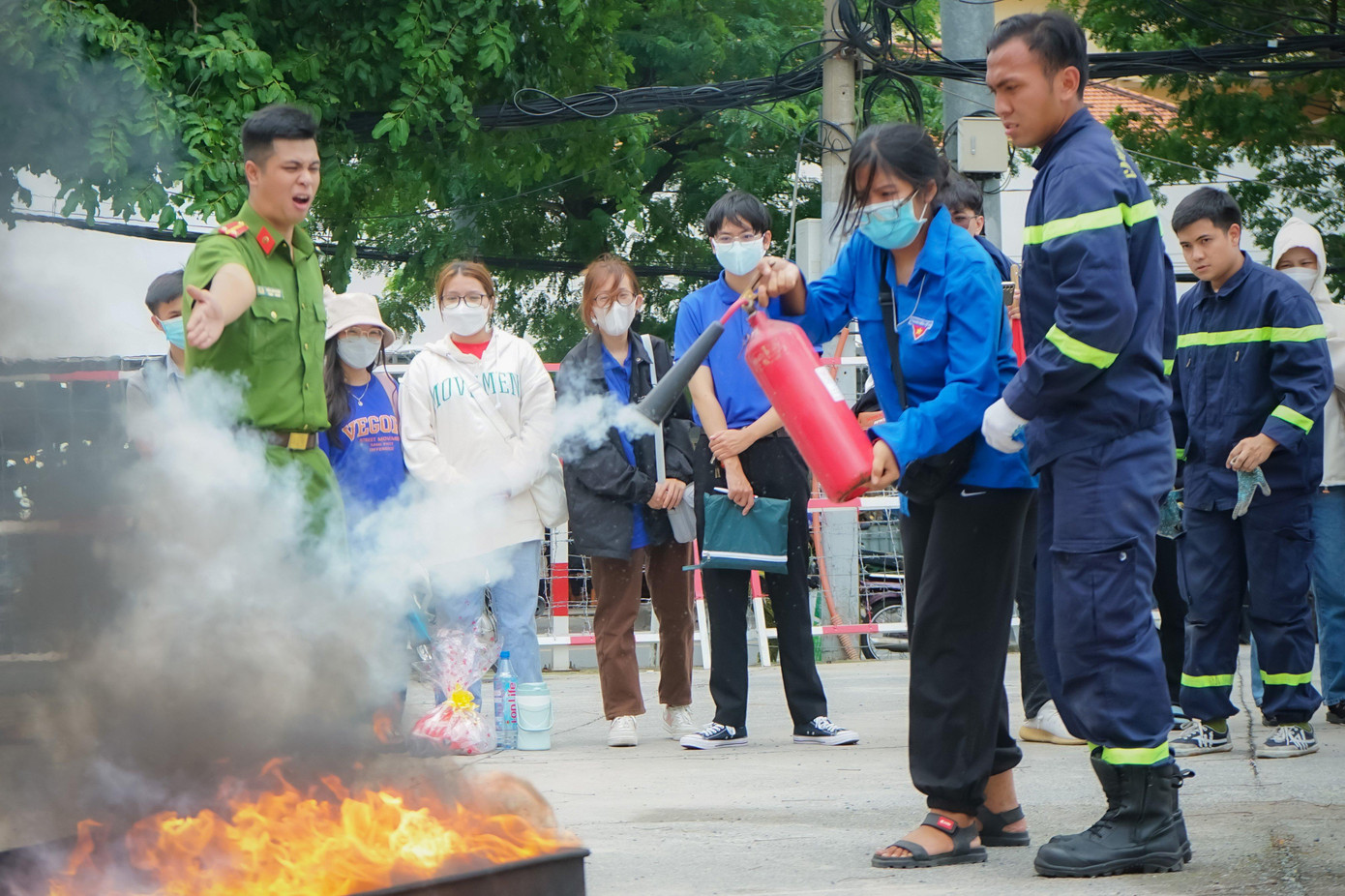 Một nữ chiến sĩ "Mùa Hè Xanh" trường ĐH Sài Gòn được các chiến sĩ công an PCCC hướng sử dụng bình chữa cháy để dập tắt đám cháy.