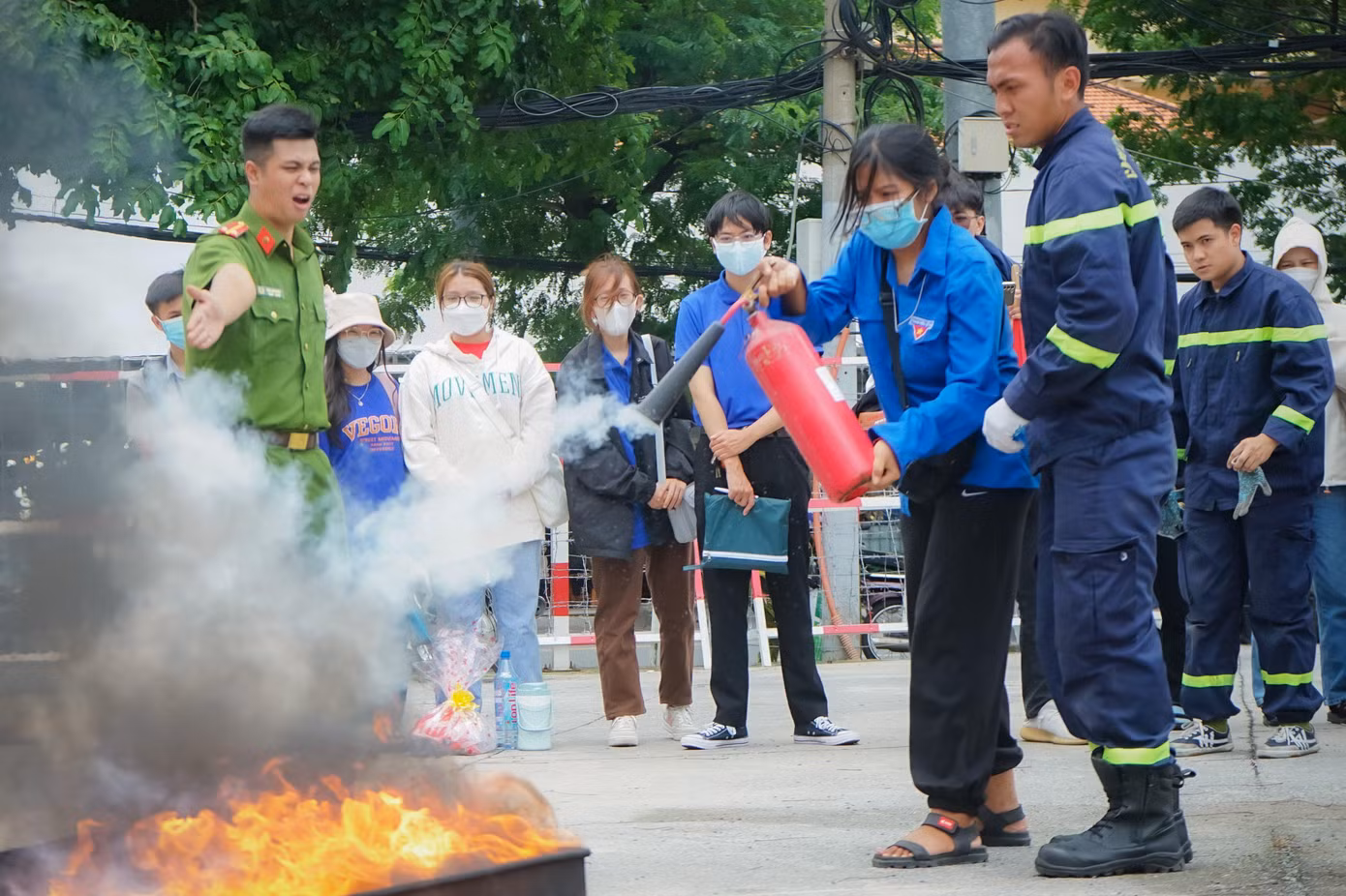 Một nữ chiến sĩ "Mùa Hè Xanh" trường ĐH Sài Gòn được các chiến sĩ công an PCCC hướng sử dụng bình chữa cháy để dập tắt đám cháy.