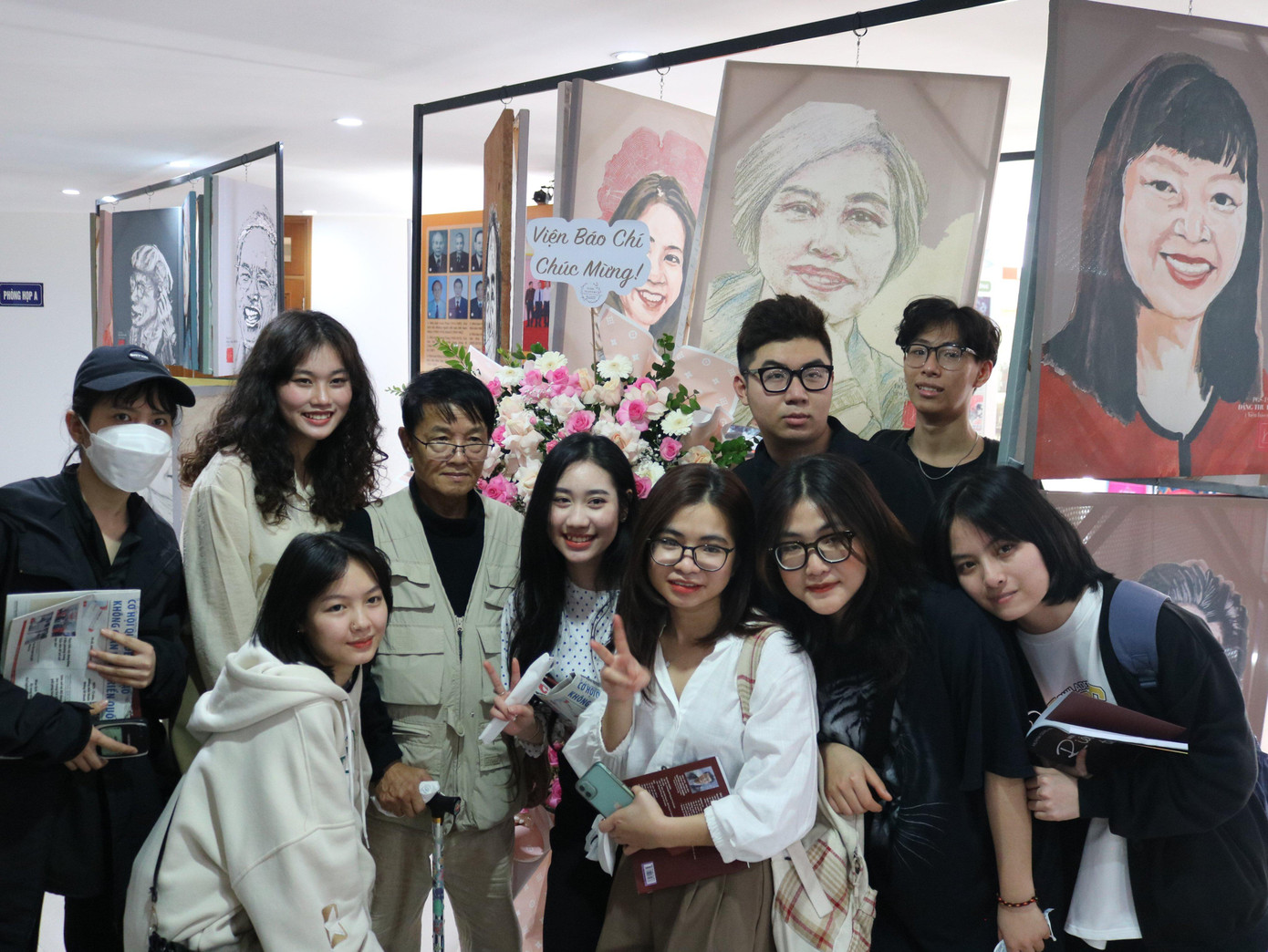 Nhà báo Huỳnh Dũng Nhân chụp hình cùng các bạn sinh viên tại triển lãm. (Ảnh: Hoàng Liên)