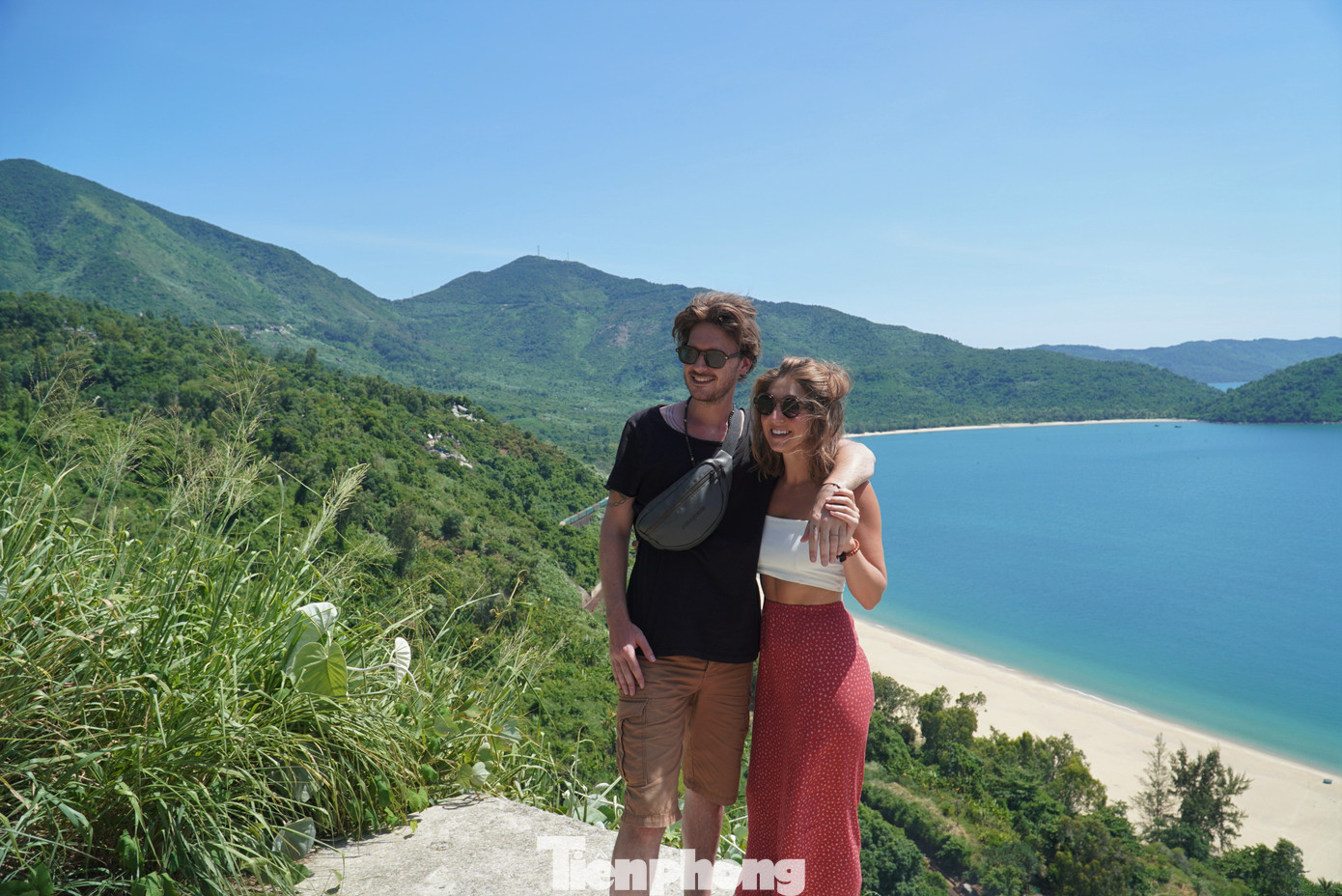 Cặp đôi du khách nước ngoài chụp ảnh lưu niệm sau khi dừng xe bên đường để ngắm nhìn đoàn tàu đi qua núi Hải Vân. Ảnh: Thanh Hiền.