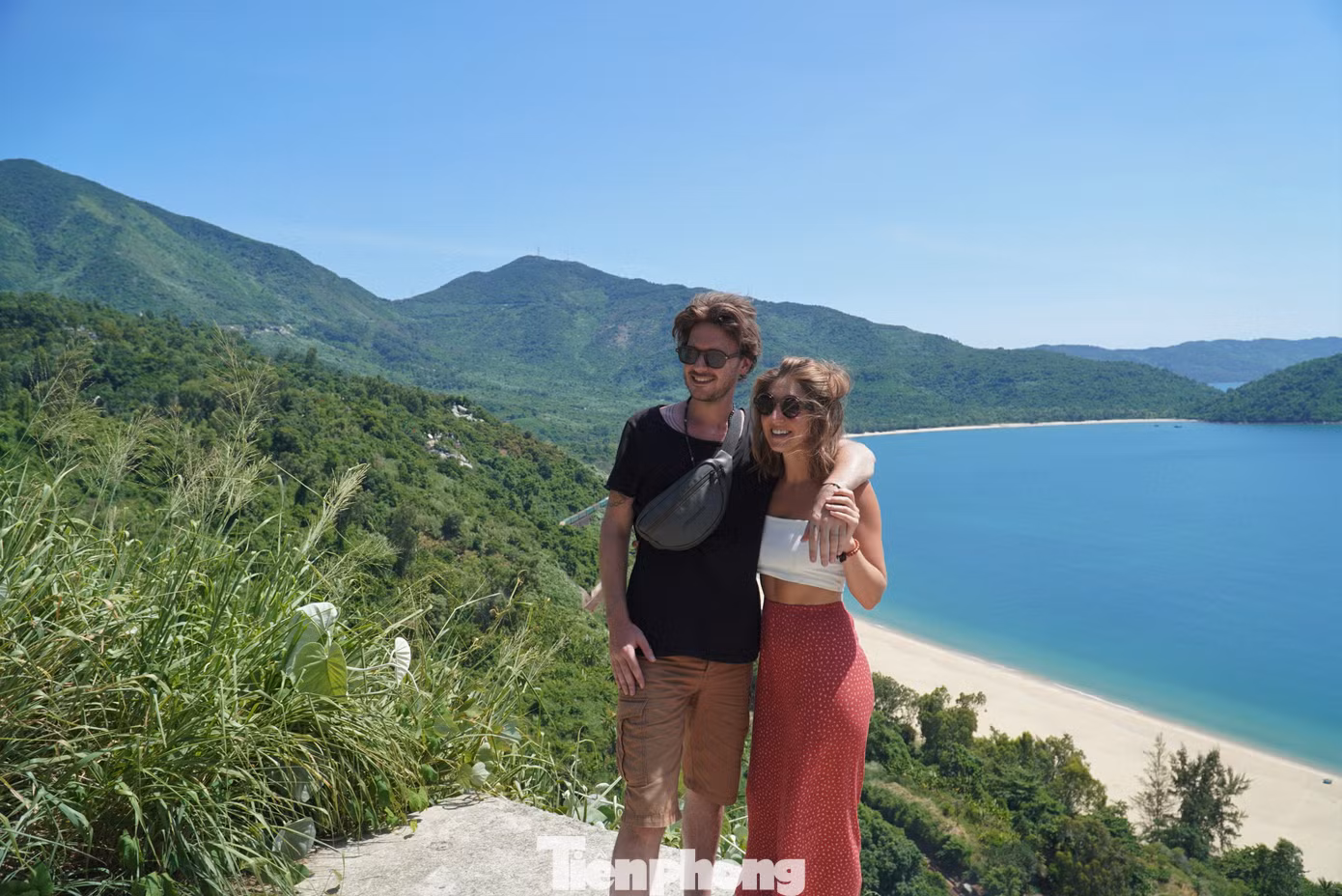 Cặp đôi du khách nước ngoài chụp ảnh lưu niệm sau khi dừng xe bên đường để ngắm nhìn đoàn tàu đi qua núi Hải Vân. Ảnh: Thanh Hiền.