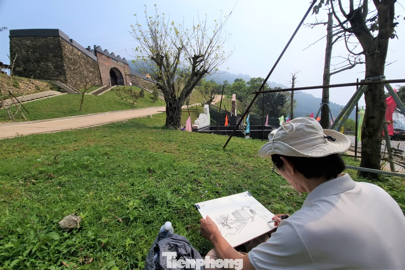 Một họa sĩ ngồi vẽ di tích Hải Vân Quan từ xa.