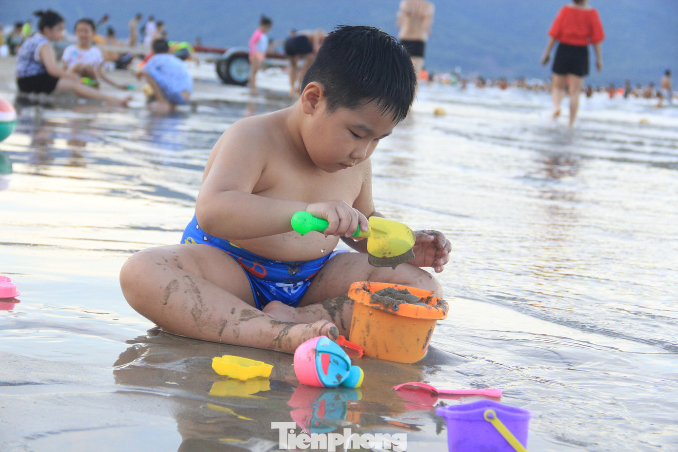 Một em nhỏ say sưa chơi đồ chơi với cát biển.