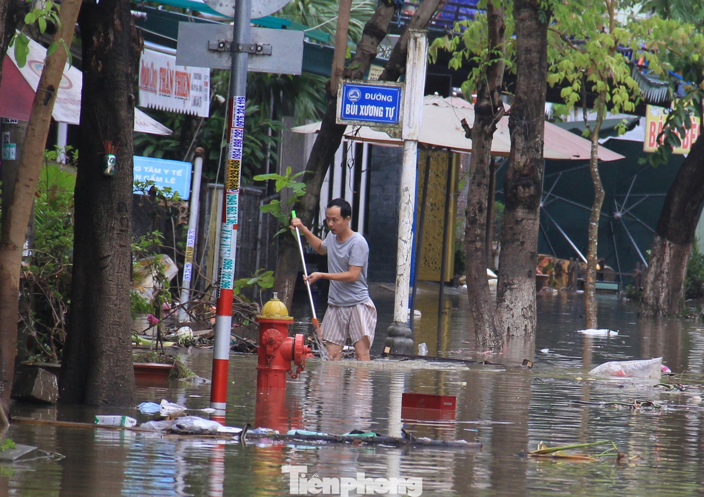 Đường Bùi Xương Tự vẫn bị nước bủa vây. Người dân tranh thủ nước rút để đẩy rác, bùn non.