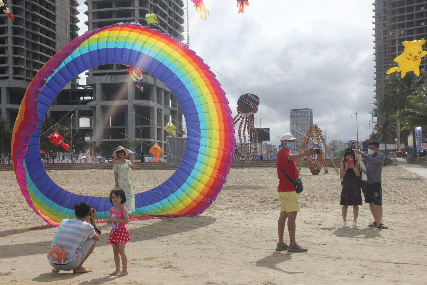 Du khách chụp ảnh với con diều khổng lồ chuẩn bị được thả trên bãi biển.