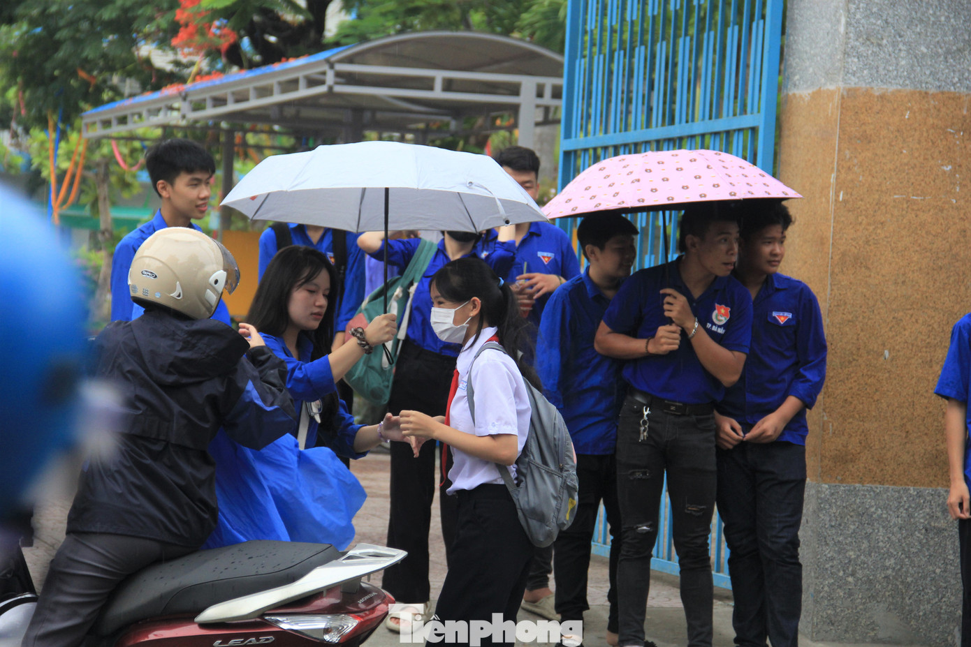 Tình nguyện viên che ô cho các thí sinh vào trường.