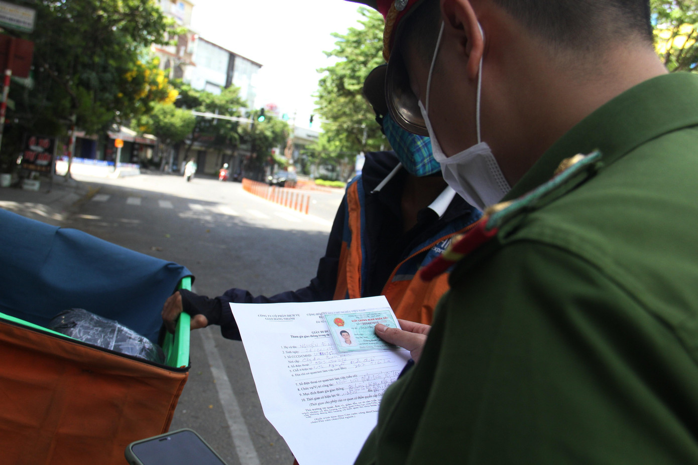 Lực lượng chức năng kiểm tra giấy đi đường của một nhân viên giao hàng. Lực lượng chức năng kiểm tra giấy đi đường của một nhân viên giao hàng.