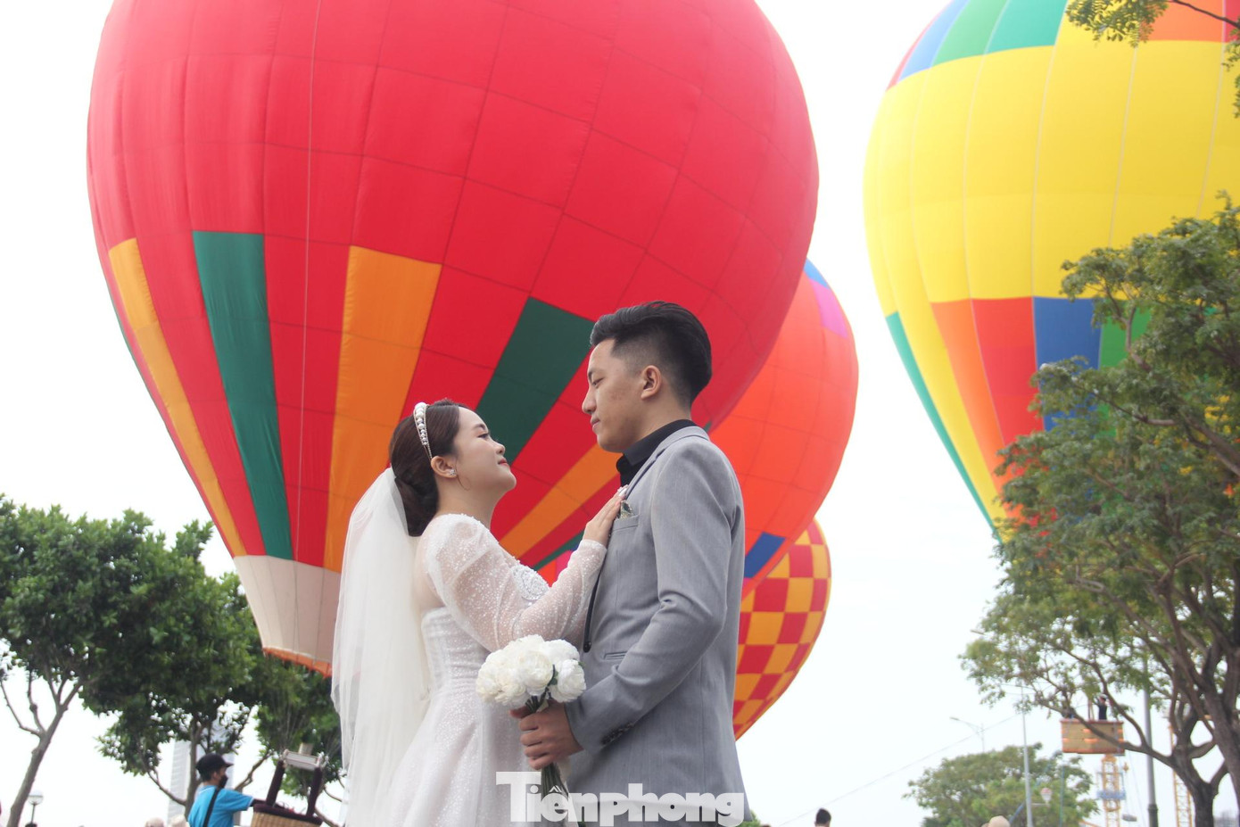 Một cặp đôi chụp ảnh cưới với khinh khí cầu.