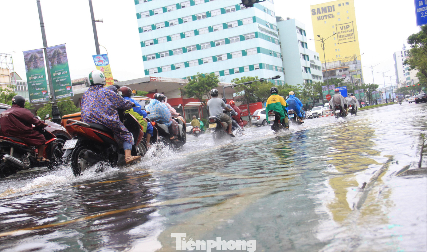 Đường Nguyễn Văn Linh nước leo lên vỉa hè, xe cộ phải ép sang làn ngoài cùng để tránh bị chết máy.