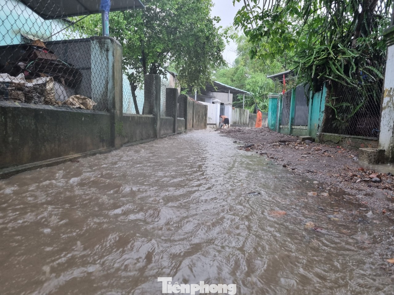 Đường bê tông đã bị nước, đất đá vùi lấp. Người dân cho biết khi nước rút, phải có xe múc hỗ trợ mới có thể dọn hết đất đá giữa đường.