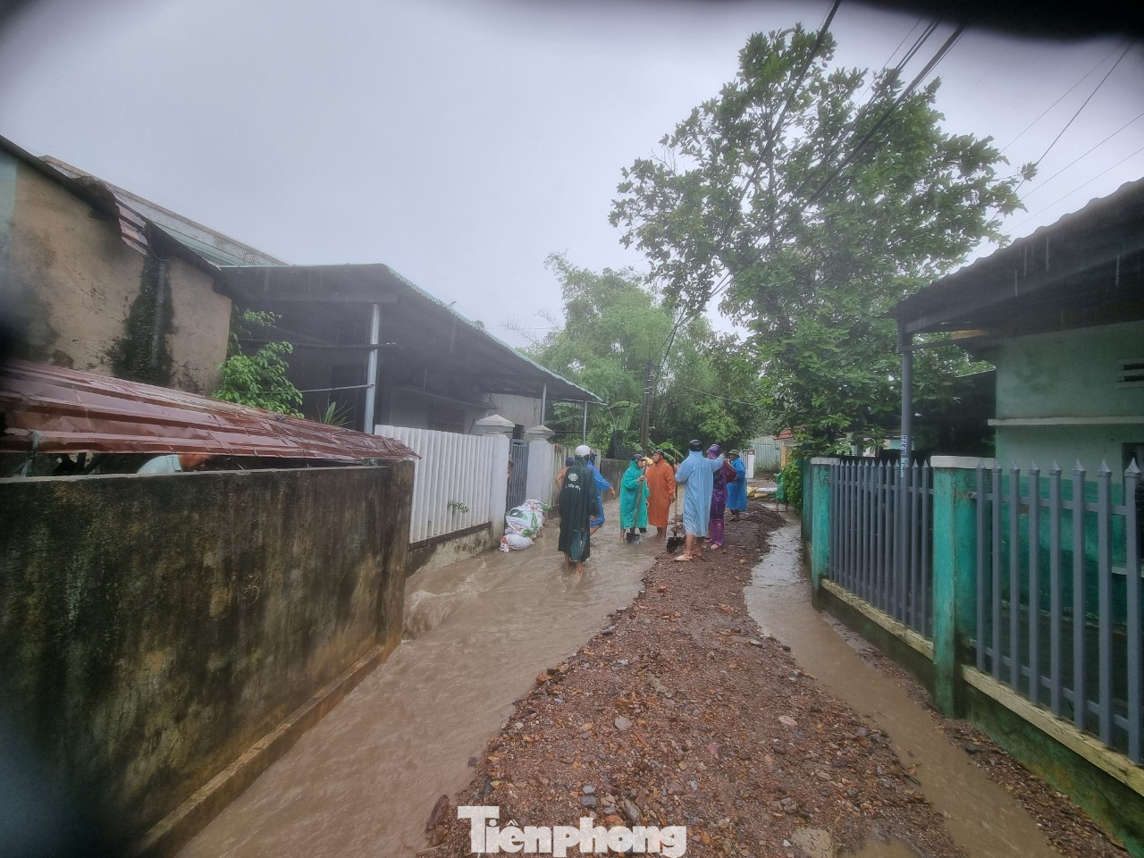 Đường bê tông đã bị nước, đất đá vùi lấp. Người dân cho biết khi nước rút, phải có xe múc hỗ trợ mới có thể dọn hết đất đá giữa đường.