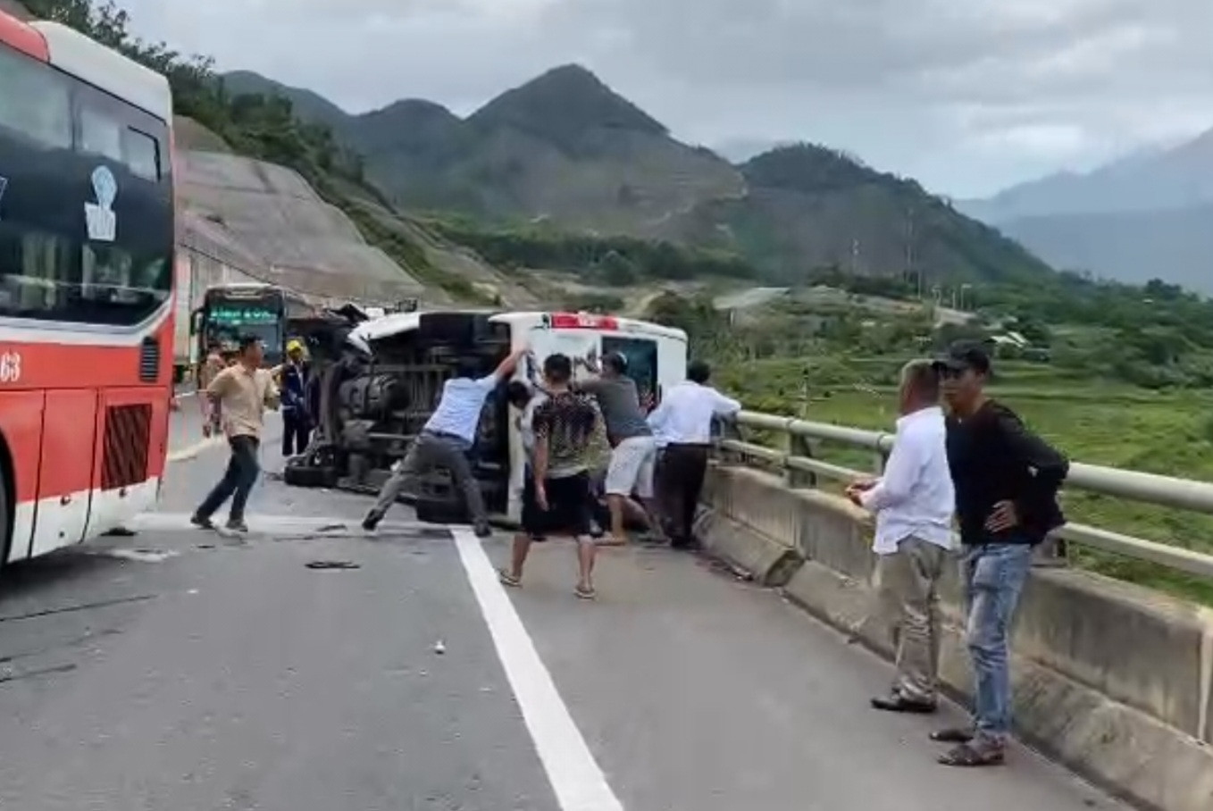 Người dân cố tìm cách đưa các nạn nhân ra khỏi xe ô tô 16 chỗ bị lật.