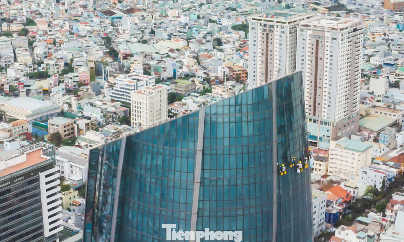 Một đội lau kính có 9 người, 3 người canh dây, 6 người lau. Phía dưới mặt đất có thêm một người giám sát. Ảnh: Nguyễn Trình.