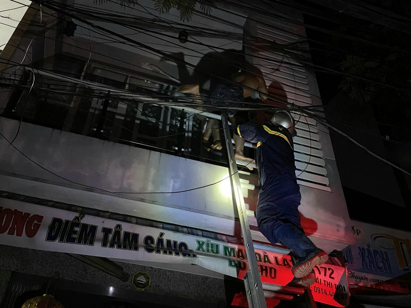 Lực lượng chức năng dùng thang đưa 4 người mắc kẹt trên ban công xuống. Lực lượng chức năng dùng thang đưa 4 người mắc kẹt trên ban công xuống.