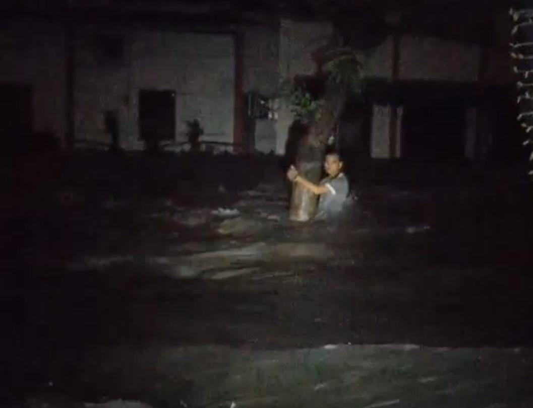 Một thanh niên bám chặt vào cây trước dòng nước hung hãn.