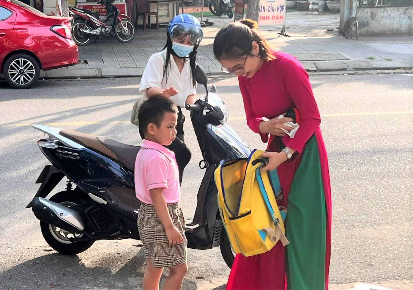 Từ sáng sớm, phụ huynh đã đưa các cháu đến trường. Trong ảnh: Cô giáo đón trẻ trước cổng trường, kiểm tra cặp, vật dụng trước trước khi vào lớp.