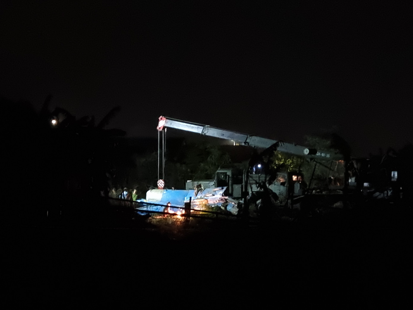 Khu vực phần đuôi máy bay rơi. Ở đây là bãi đất trống, bên cạnh vườn của các hộ dân. Tại hiện trường, xe cẩu, máy cắt cùng các thiết bị khác đã được đưa vào. Hàng chục chiến sĩ, công nhân tiến hành cưa cắt phần đuôi máy bay. (Ảnh: Thanh Trần).