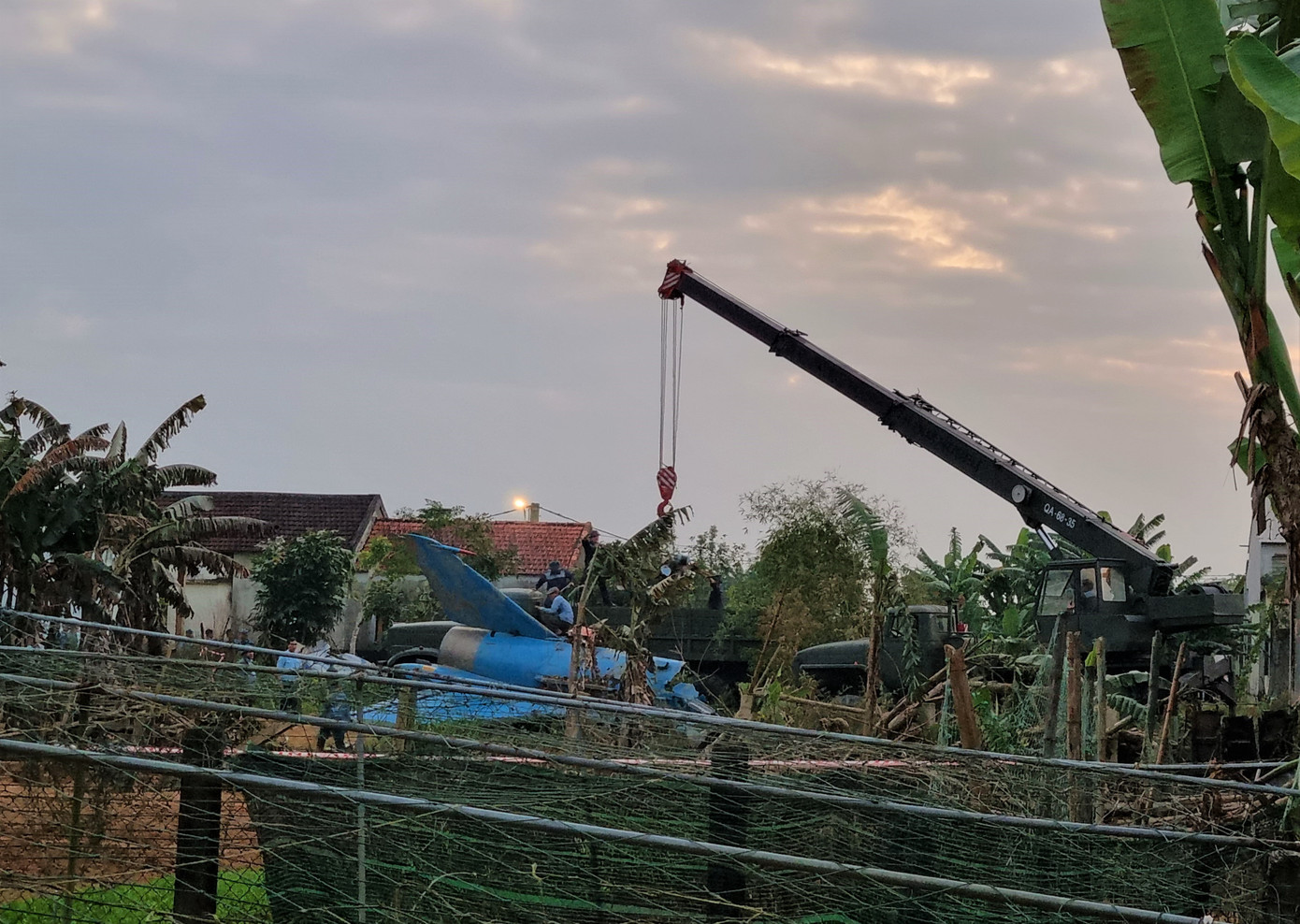 Khi phi công báo máy bay gặp sự cố, không thể về hạ cánh được, chỉ huy bay lệnh cho phi công cố gắng đưa máy bay ra khỏi khu đông dân cư và nhảy dù. Đại úy phi công Đỗ Tiến Đức đã nỗ lực đưa máy bay ra xa khu dân cư và nhảy dù an toàn. Trong ảnh: Phần đuôi máy bay nằm ngay khoảng đất trống, xung quanh là nhà dân. (Ảnh: Thanh Trần).