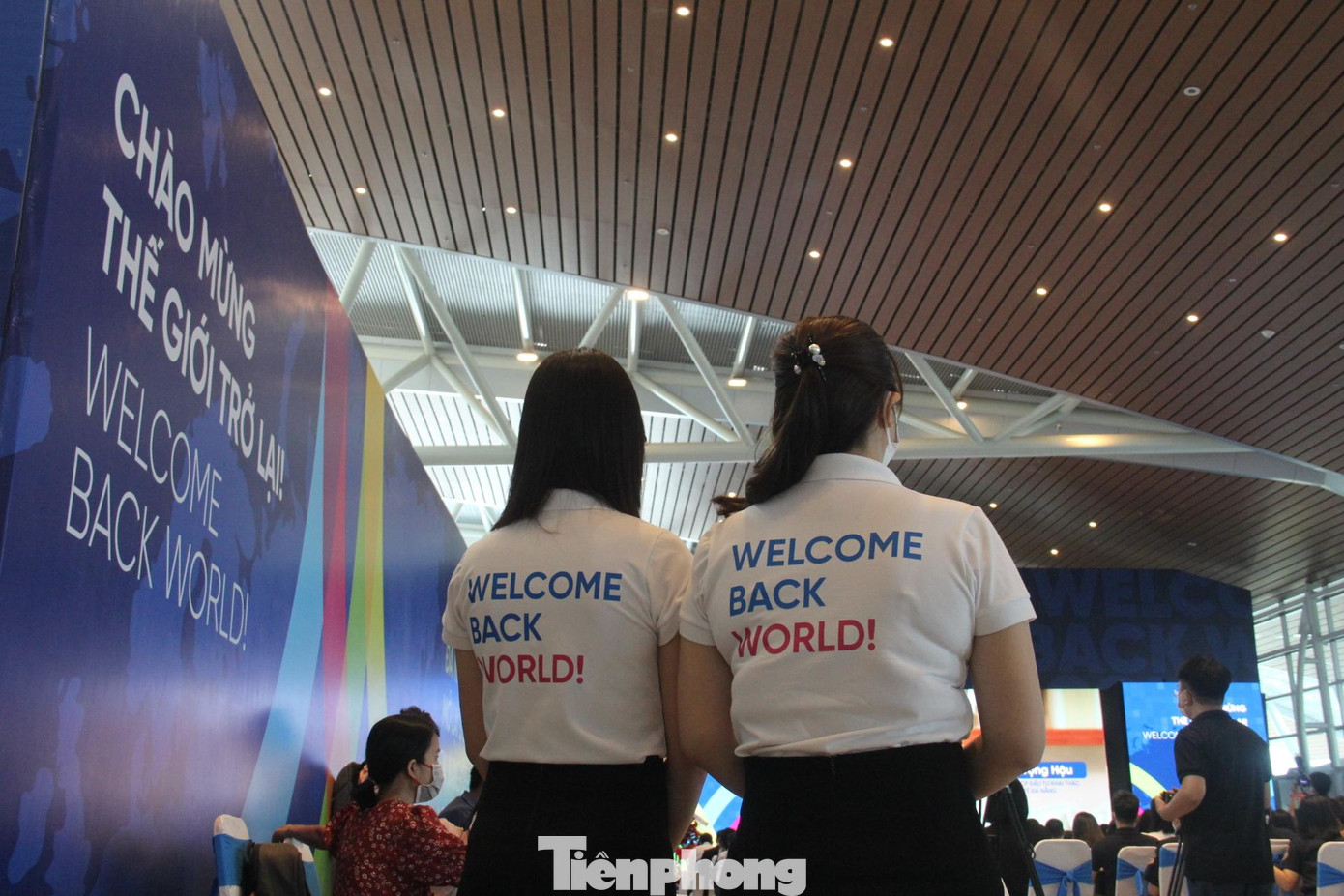Nhân viên sân bay mang áo với dòng chữ "Wekcome back world!" trong ngày đầu tiên đón chuyến bay chở du khách quốc tế.