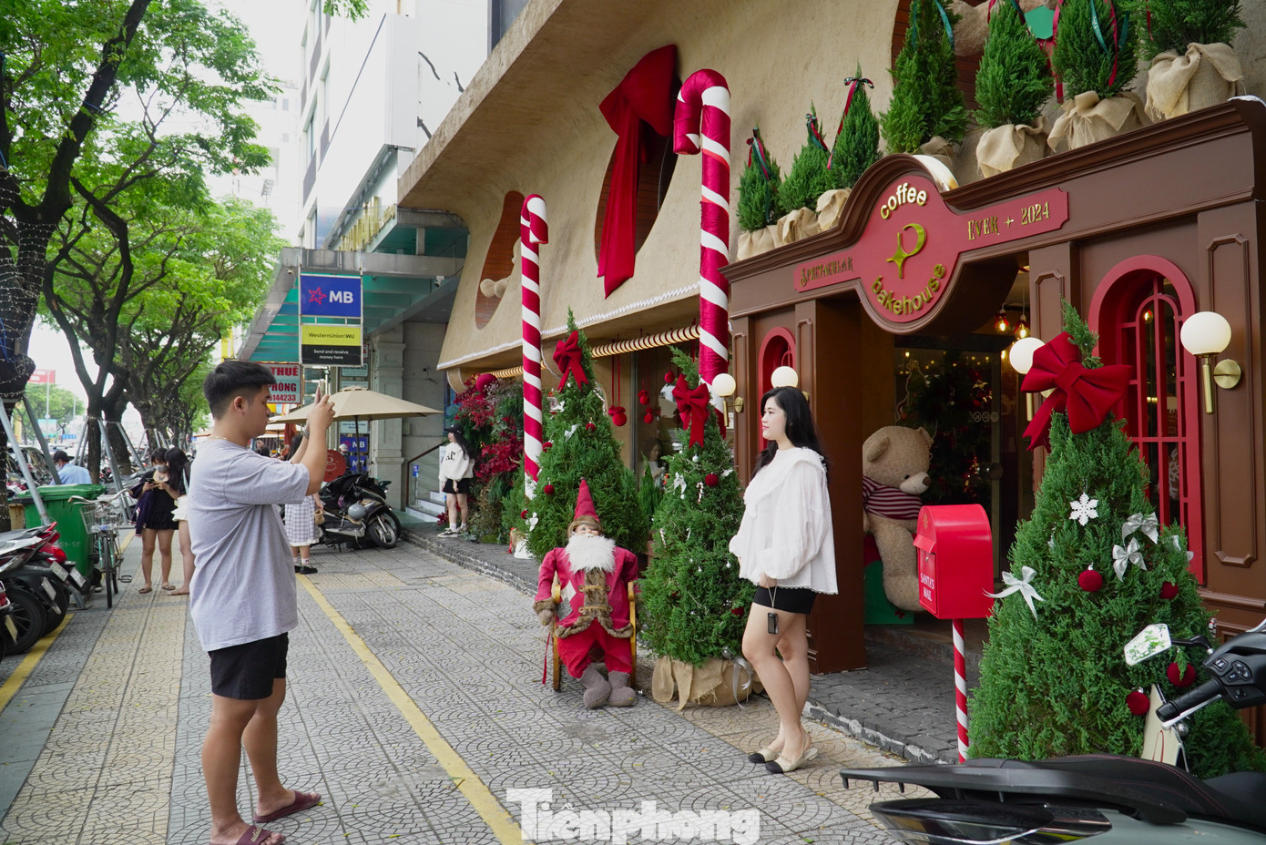Tuyến đường Nguyễn Văn Linh ngay trung tâm thành phố có hàng loạt cửa hàng đã “khoác áo” đỏ rực của mùa Giáng sinh năm nay. Từ sáng sớm, rất đông bạn trẻ đến chụp ảnh với cây thông, ông già Noel. Ảnh: Thanh Hiền