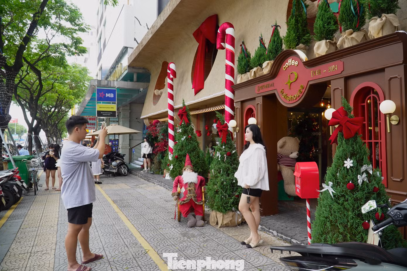Tuyến đường Nguyễn Văn Linh ngay trung tâm thành phố có hàng loạt cửa hàng đã “khoác áo” đỏ rực của mùa Giáng sinh năm nay. Từ sáng sớm, rất đông bạn trẻ đến chụp ảnh với cây thông, ông già Noel. Ảnh: Thanh Hiền
