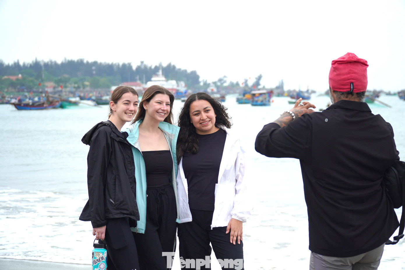 Cùng đi dạo trên tuyến đường ven biển, một nhóm du khách Mỹ đã rủ nhau dừng lại ở bãi biển Thọ Quang khi thấy bên dưới có cả trăm chiếc thuyền đang neo lại. Vừa xuống tới bãi cát, cả nhóm thay nhau chụp hình với khung cảnh thuyền phía sau lưng. Ảnh: Thanh Hiền.