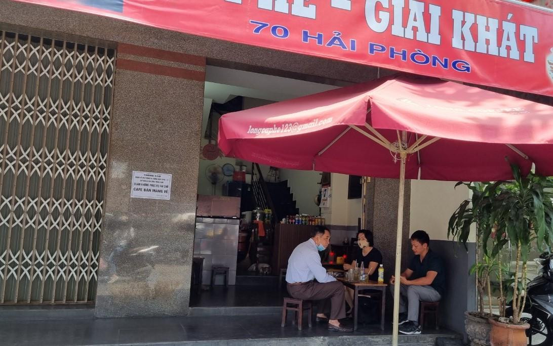 Một số quán đã đóng hết cửa khu vực khách ngồi, chỉ chừa lại phần quầy giao hàng. Trong ảnh: Một quán cà phê trên đường Hải Phòng phục vụ những người khách cuối cùng trước khi chỉ bán mang về. Ảnh: Thanh Trần.