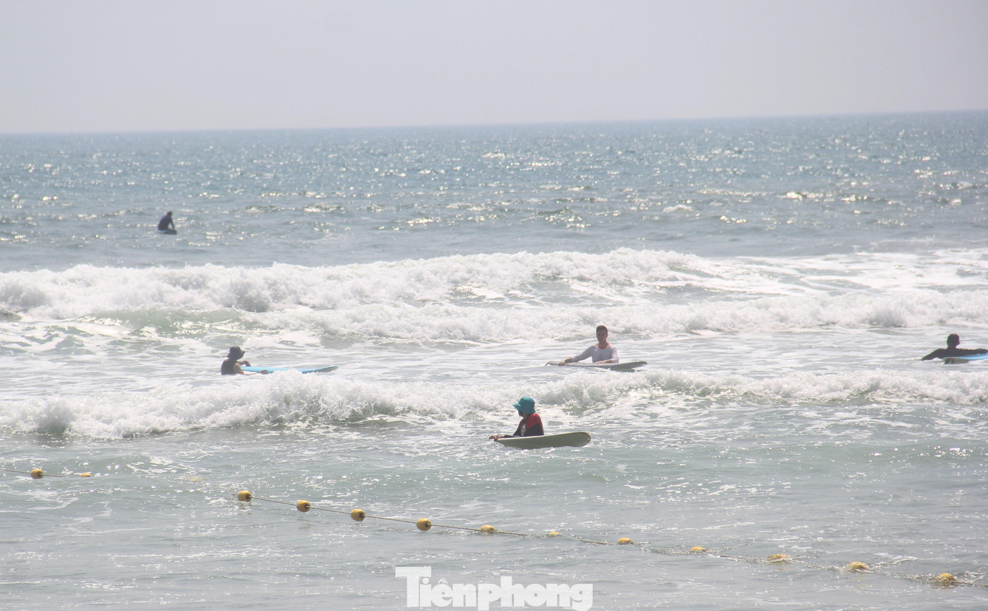 Trời nắng nóng, nhiều người vẫn xuống biển chơi lướt ván. Ảnh: Thanh Trần.