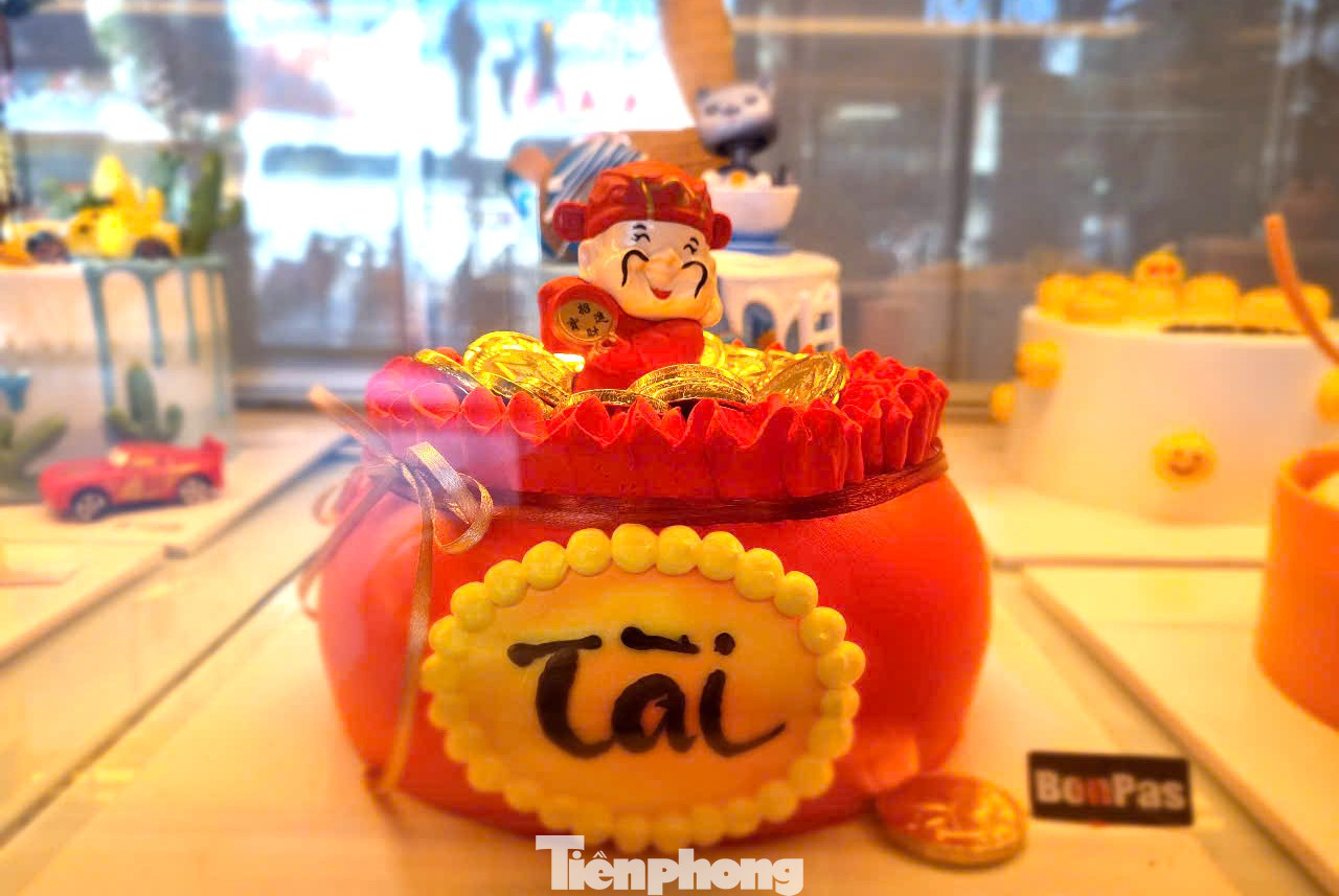 Ghi nhận của Tiền Phong, các tiệm bánh tung ra nhiều mẫu bánh kem trong ngày vía Thần tài với hai màu chủ đạo là vàng, đỏ tượng trưng cho phú quý, may mắn. Bánh có nhiều hình thù như hình tròn, hình thỏi vàng... Tuy nhiên khách chuộng nhất là bánh hình hũ tiền. Ảnh: Thanh Hiền. Ghi nhận của Tiền Phong, các tiệm bánh tung ra nhiều mẫu bánh kem trong ngày vía Thần tài với hai màu chủ đạo là vàng, đỏ tượng trưng cho phú quý, may mắn. Bánh có nhiều hình thù như hình tròn, hình thỏi vàng... Tuy nhiên khách chuộng nhất là bánh hình hũ tiền. Ảnh: Thanh Hiền.