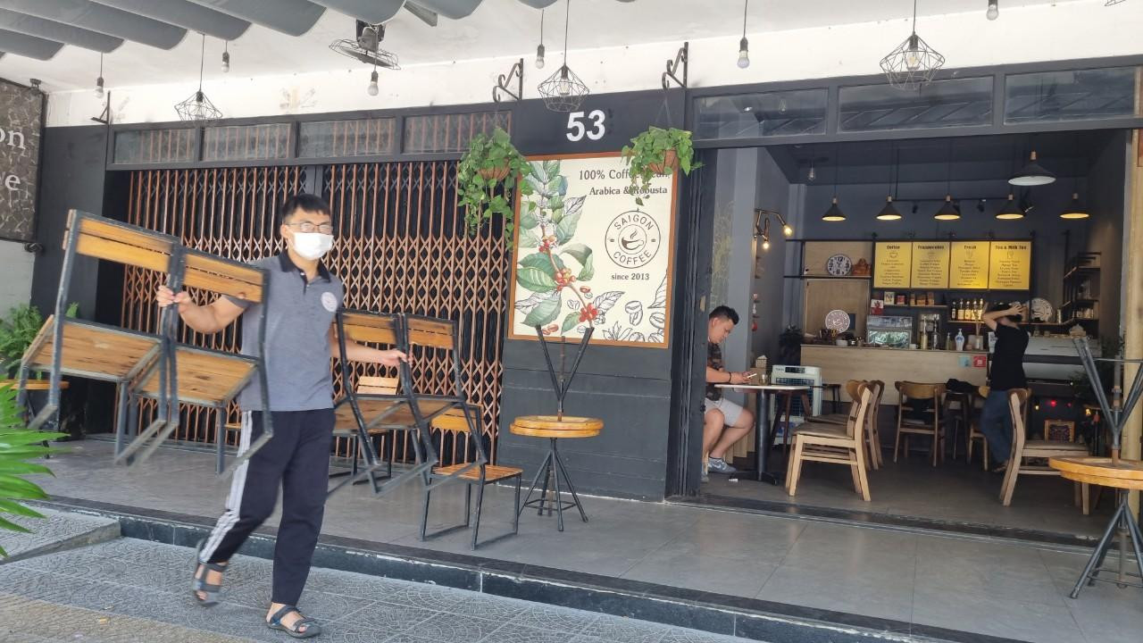 Nhân viên một quán giải khát thu dọn bàn ghế trước 12h trưa 7/5. Ảnh: Thanh Trần.