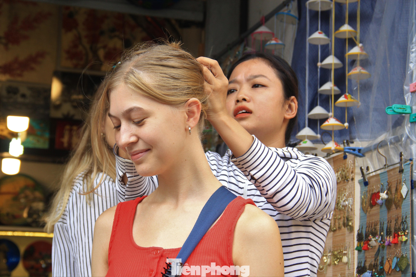 Hội An không chỉ đẹp, yên bình mà con người còn rất thân thiện, gần gũi. Trong ảnh: Một tiểu thương búi lại tóc cho du khách nước ngoài.