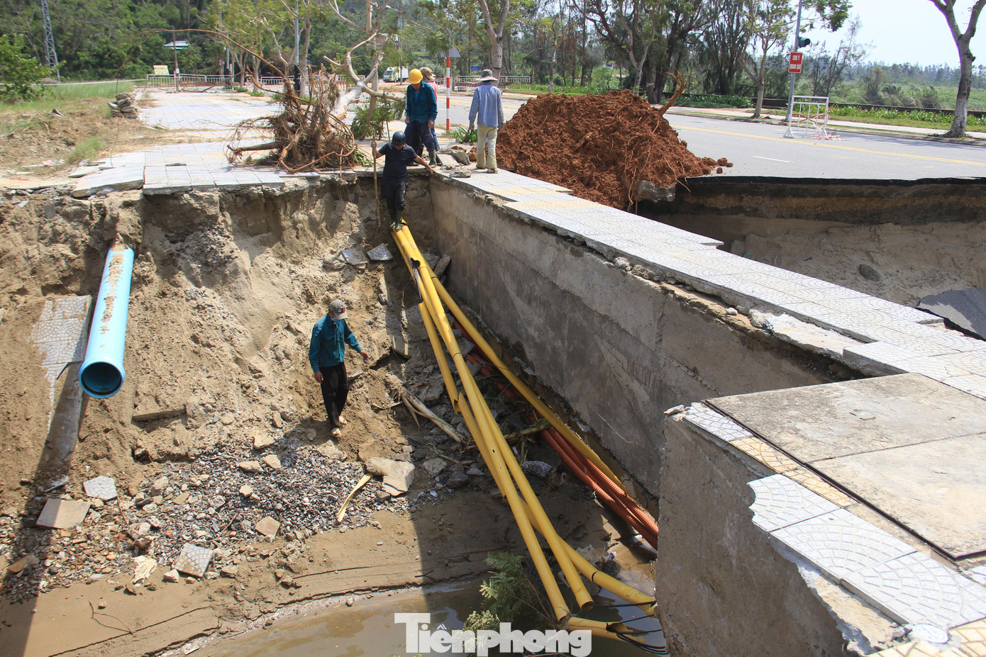 Đường sụp xuống thành hố sâu hơn 2 mét, lòi dây cáp, ống nước. Công nhân có mặt dọn đống đổ vỡ những ngày qua.