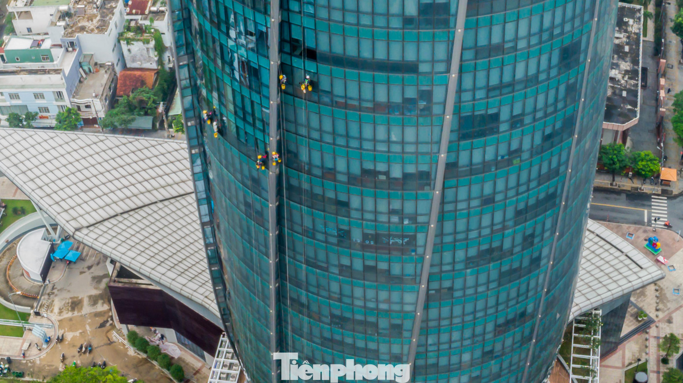 Những ngày cuối năm, khi các tòa nhà cao tầng tại Đà Nẵng có nhu cầu làm mới cũng là lúc những người công nhân lau kính lại tất bật với công việc của mình. Vì thường xuyên làm việc trên cao nên nhiều người ưu ái gọi họ là "người nhện". Họ phải làm việc trên độ cao hàng chục mét, thậm chí đến hàng trăm mét so với mặt đất. Trong ảnh: Một đội thợ đang tiến hành lau kính tòa nhà Trung tâm hành chính TP Đà Nẵng - tòa nhà 34 tầng. Ảnh: Nguyễn Trình.