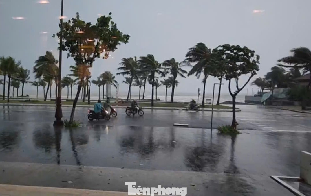 Người đi xe máy đứng lại trên đường biển vì gió quá mạnh không thể chạy tiếp.