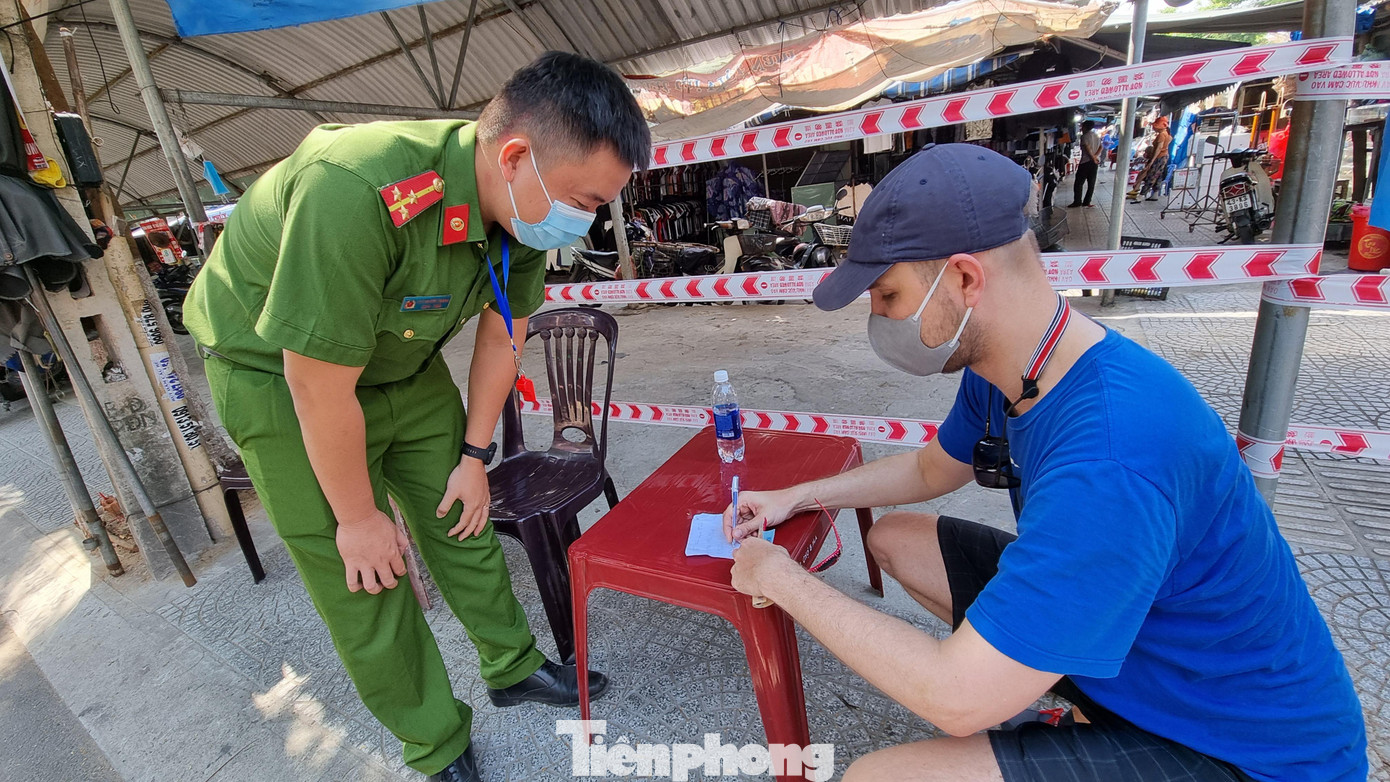 Một người Ba Lan được chiến sĩ công an hỗ trợ khai thông tin trước khi vào chợ. Ảnh: Thanh Trần.