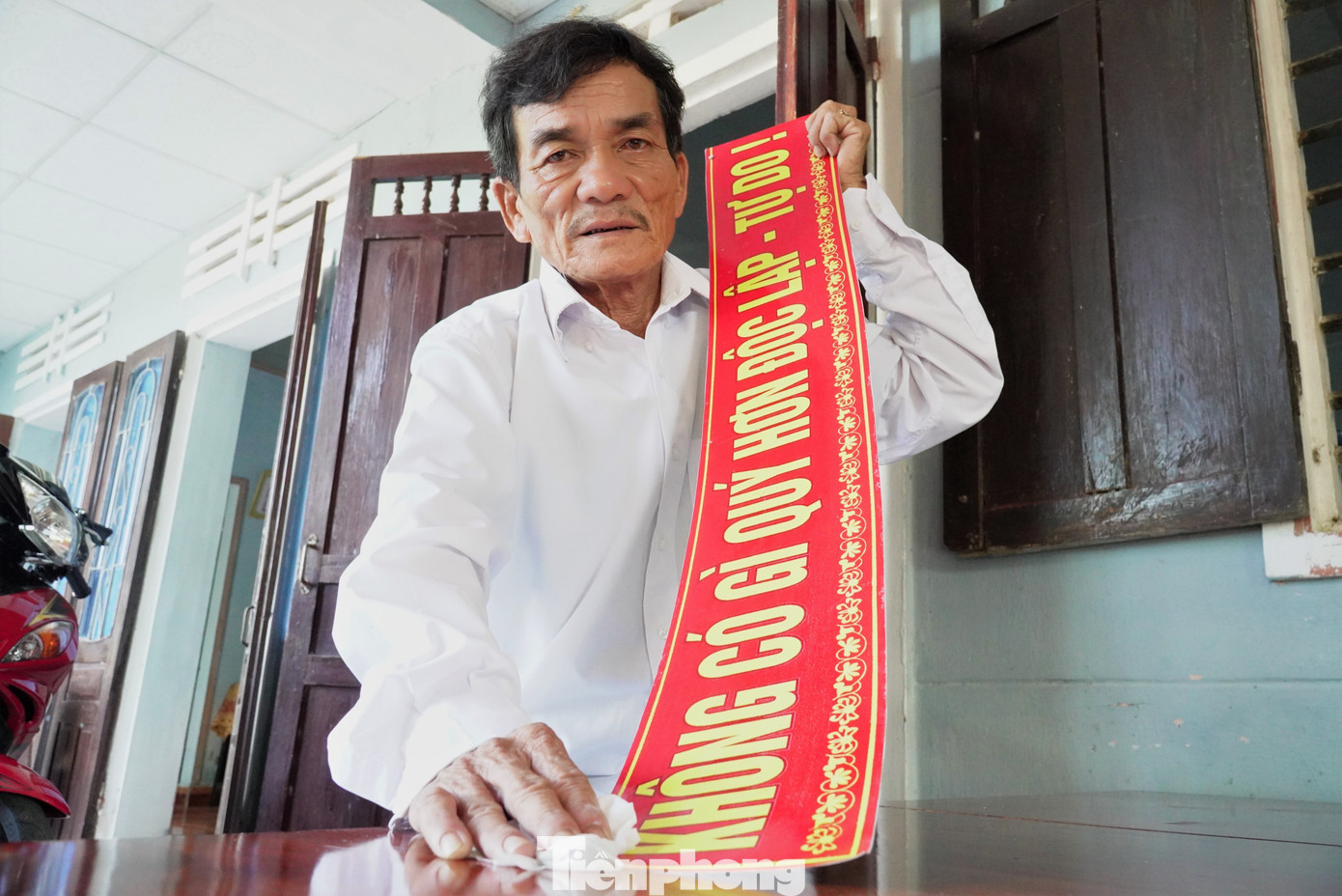 Ông Nguyễn Trường Thiệt (60 tuổi, thôn Lý Trường, xã Bình Phú) lau chùi tấm bảng sáng bóng trước khi treo lên lại. Ảnh: Thanh Hiền.