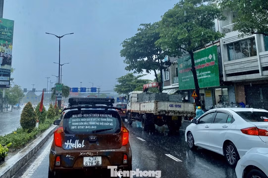 Một số tuyến đường ở trung tâm thành phố bì bõm nước, xe cộ nhích từng chút di chuyển trong cơn mưa. Ảnh: Thanh Hiền.